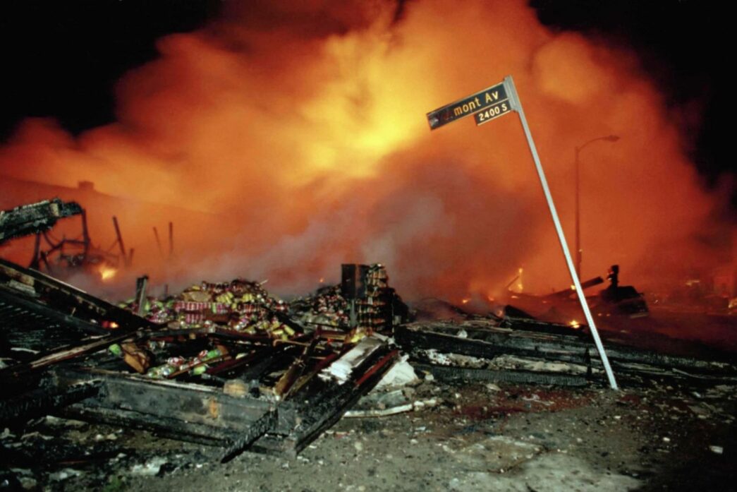 Los restos humeantes de un edificio comercial apenas se distinguían entre la densa nube de humo, mientras otra construcción ardía sin control en las primeras horas del 30 de abril de 1992 en Los Ángeles